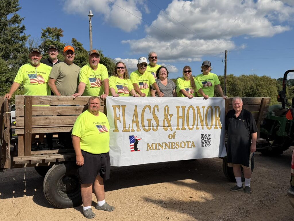 Flags & Honor of Minnesota volunteer members gather behind the organization's banner during a community event.