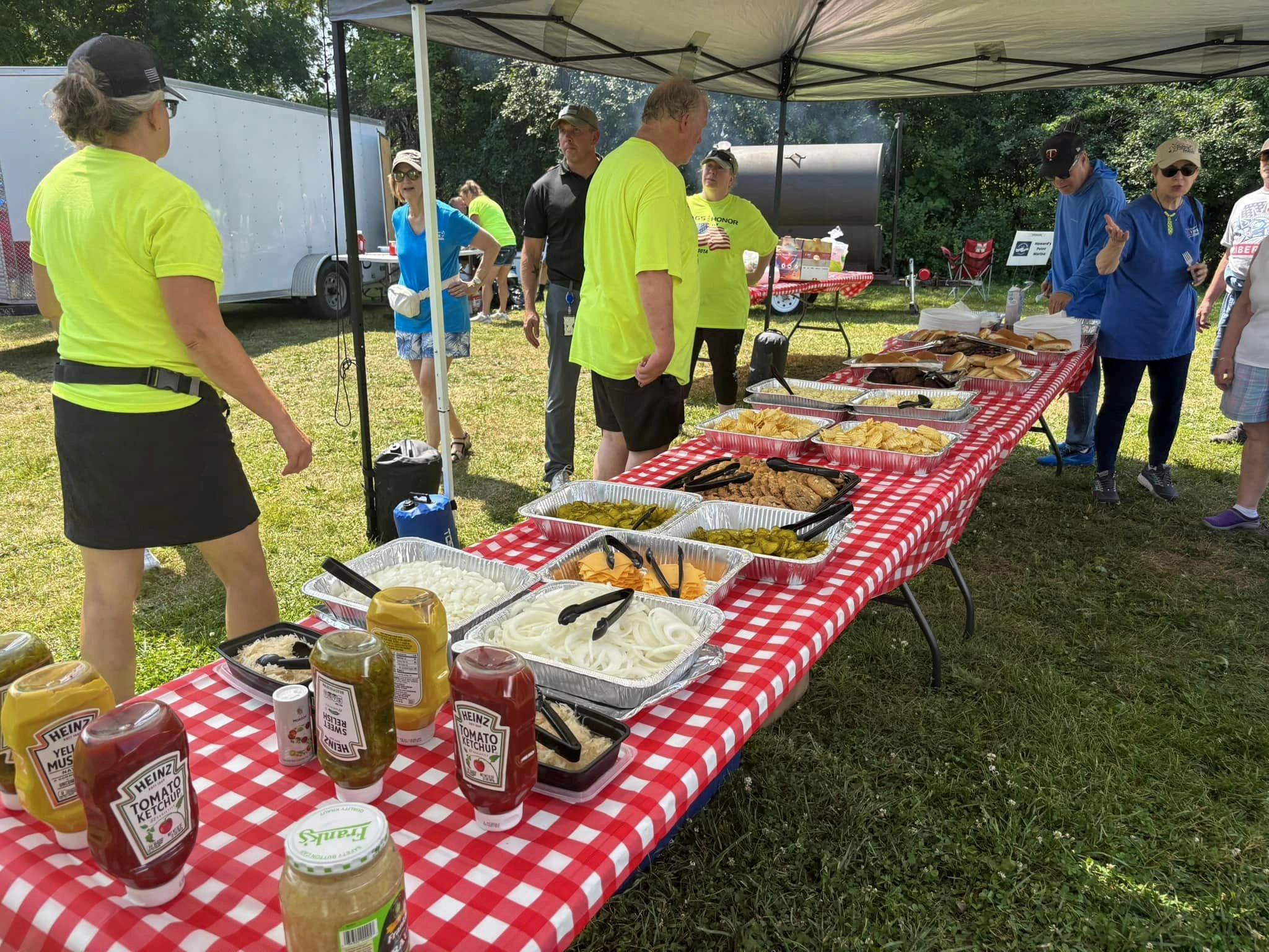 Food and barbecue on a red-and-white checkered tablecloth for a meal prepared by Flags & Honor of Minnesota for the Vets on the Lake event.