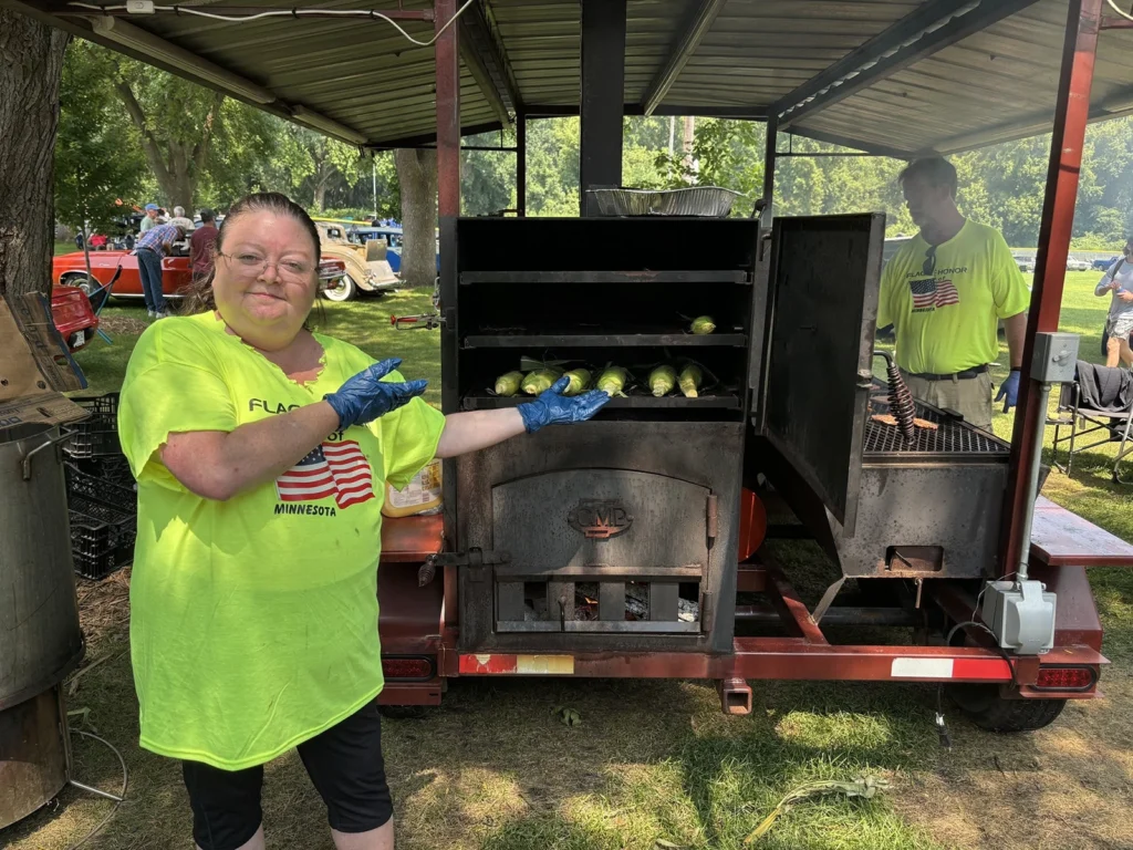 Flags & Honor of Minnesota volunteers grill sweet corn in the organization's outdoor kitchen during the Car Show.