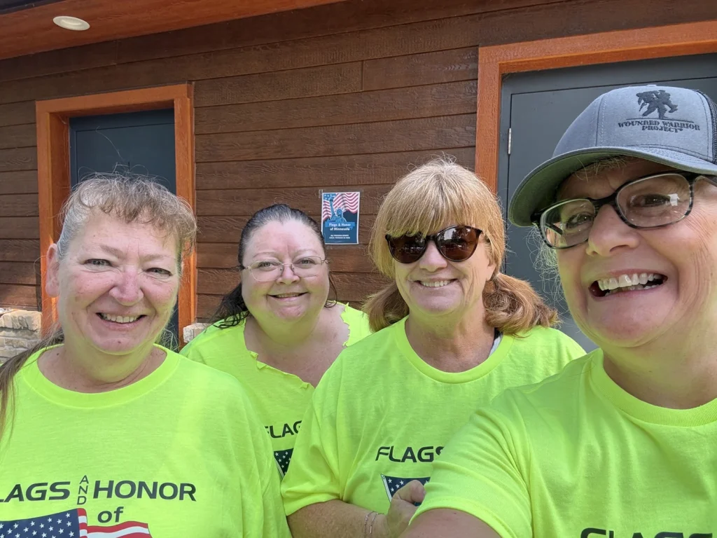 Four Flags & Honor of Minnesota volunteers wearing matching shirts smile together.
