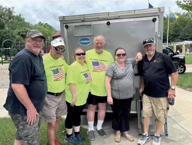 Group shot of 6 members of the Flags and Honor team standing behind a trailer.