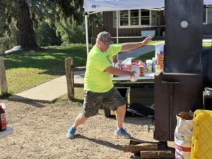 Flags & Honor member fanning the flames of an outdoor grill
